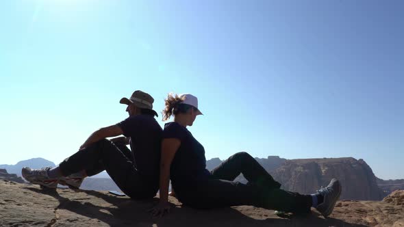 Couple of hikers sitting at the edge of mountains