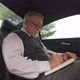 4K Senior businessman sitting on car back seat and writing business plan in the book