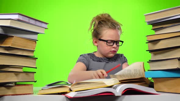 Little Girl Sitting at the Table and Nervously Throws Book. Green Screen alt