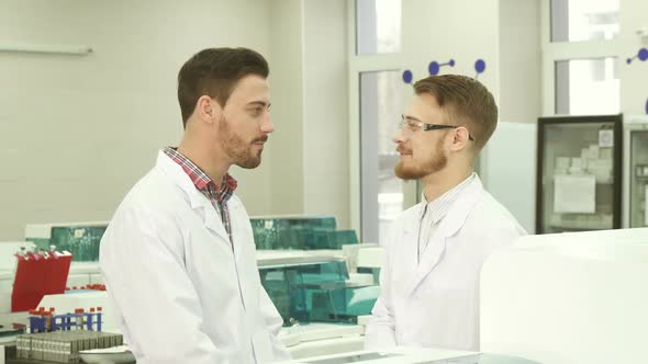 Two Colleagues of Laboratory Assistants Communicate During a Break at Work alt