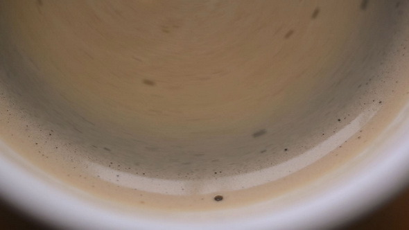 Stirring Fresh Coffee in a Cup with Foam
