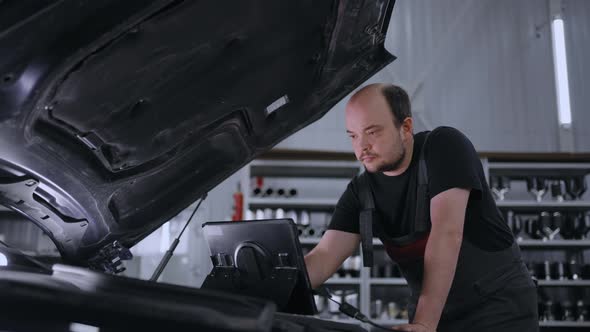 Male Mechanic Uses a Tablet Computer with an Augmented Reality Diagnostics Software alt