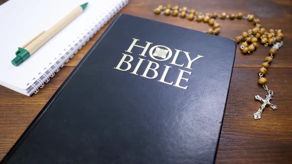 Holy Bible with Beads with Crucifix on Brown Wood Table Background