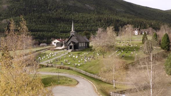 Norwegian Landscape With Old Wooden Church And Graves In Sel, Norway - aerial drone shot alt