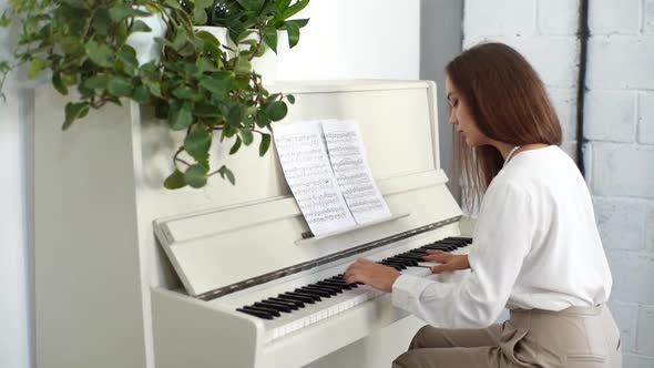 Tracking Shot of Focused Young Female Musician Playing on White Classical Piano Energetic Music at alt