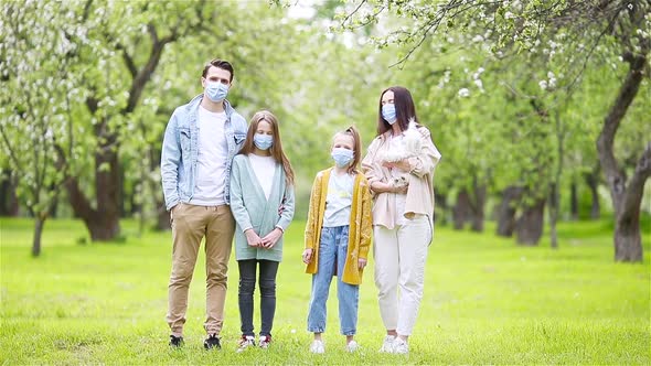 Adorable Family in Blooming Cherry Garden in Masks