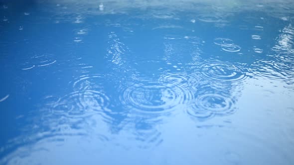 Circles of Raindrops on the Surface of the Blue Water. Abstract Background. Rain in the Swimming