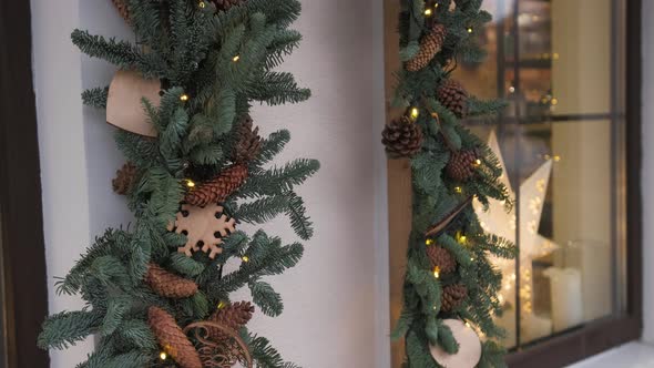 Windows decorated to Christmas with christmas trees fir branches, decorations and garland lights alt