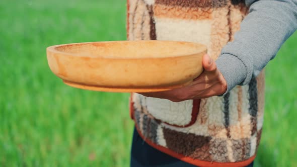 A Young Peasant Man Is Sowing the Field with Grain at a Village. A Farm Concept. alt