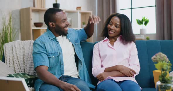 African American Couple Posing on Camera with Huggs on Home Interior Background alt