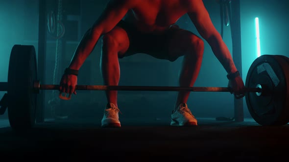 Male Powerlifter in a Blueorange Neon Light is Preparing for a Workout in the Gym alt
