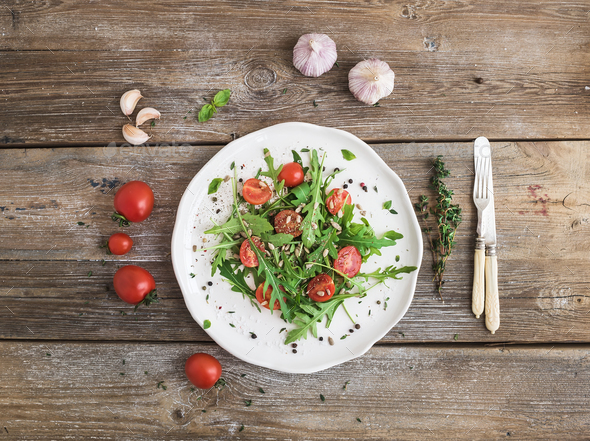 Salad with arugula, cherry tomatoes, sunflower seeds and herbs on white ceramic plate - Stock Photo - Images