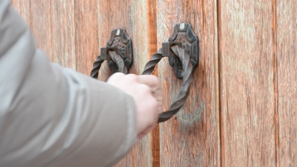 Hand Knocking On Old-fashioned Ancient Wooden Gate