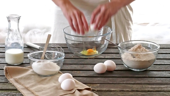 Woman Breaking Eggs Into a Bowl. Rustic Style.