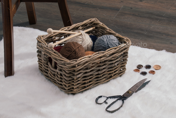 scissors and yarn ball inside old basket on carpet