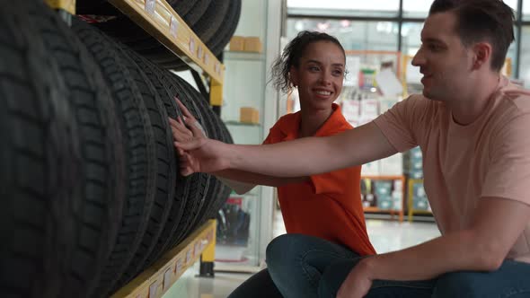 technician service person working in garage car to recommend and sell a tire on shelf storage alt