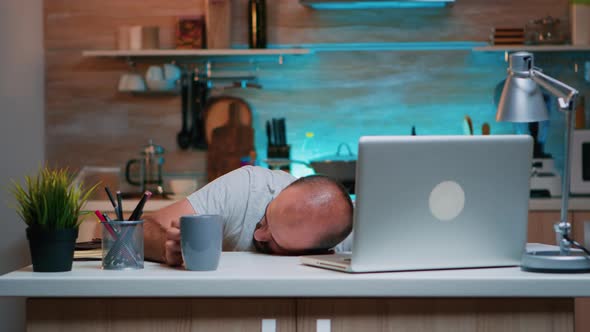 Overworked Man Sleeping on Kitchen Desk alt