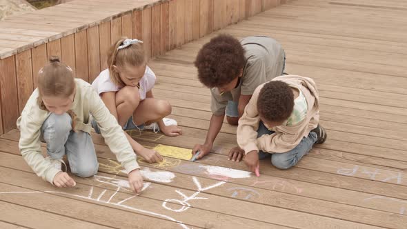 Multiethnic Kids Drawing with Chalk Outdoors alt