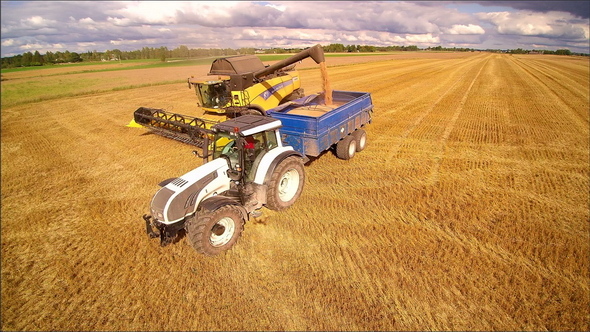 A Yellow Harvester and a Truck Fully Loaded with Grains