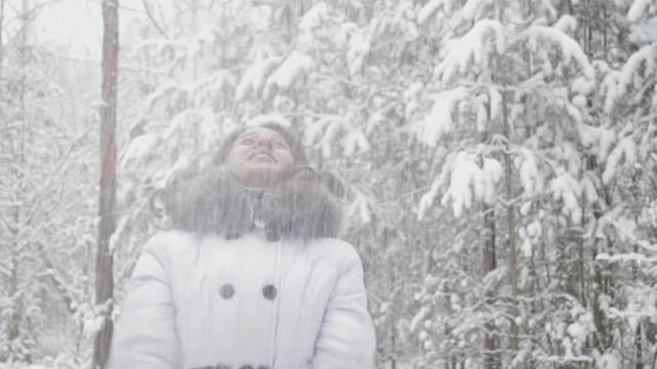 Girl Throws Snow Up in a Snowy Forest