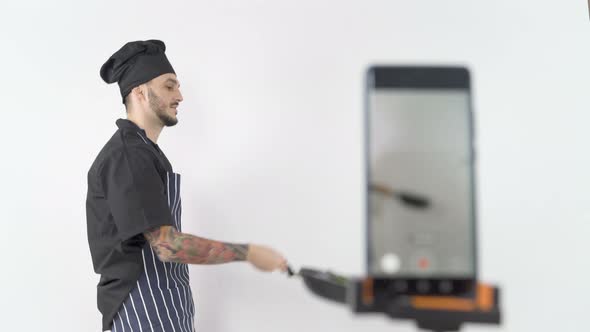 Professional Male Chef Tossing Vegetables in Wok During Online Lesson alt