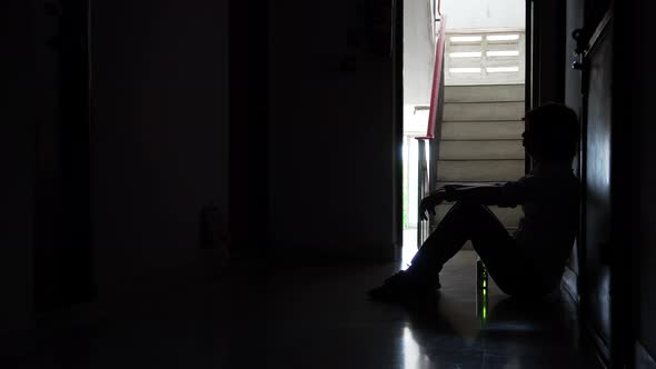 Silhouette of man sitting alone, Sad and Serious and holding a bottle of alcohol and drinking beer  alt