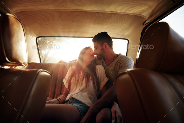 Romantic young couple in back seat of car