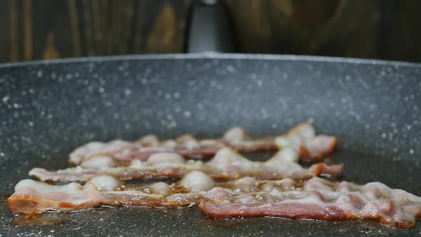 Bacon is Fried in a Frying Pan Closeup in Slow Motion