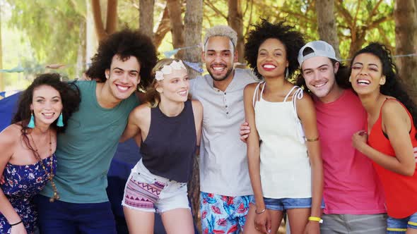 Friends standing together with arm around in park alt