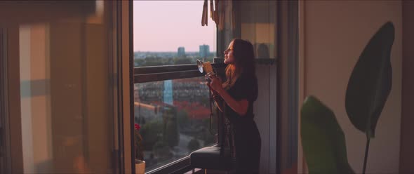 Woman photographer taking a picture from the balcony during golden hour alt