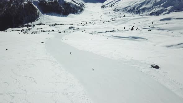 Aerial drone view of a skier skiing on top of a snow covered mountains in the winter. alt