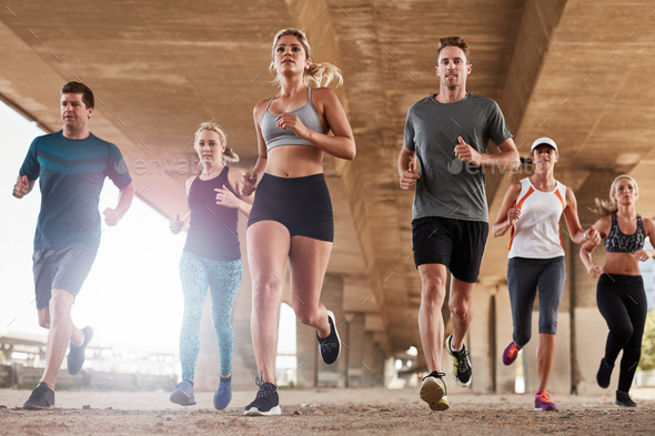 Determined group of young people running in city Stock Photo by