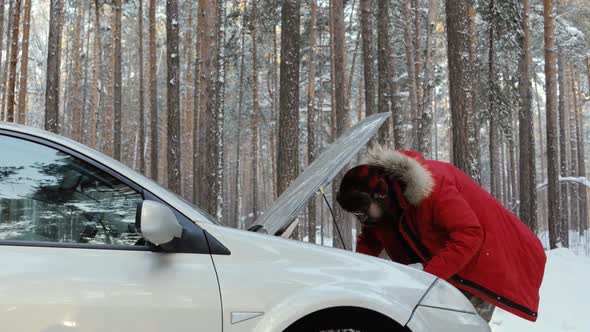 Man Looking at Engine of Car. Man Repairing Broken Car. Winter Driving, Trouble on a Snowy Country alt
