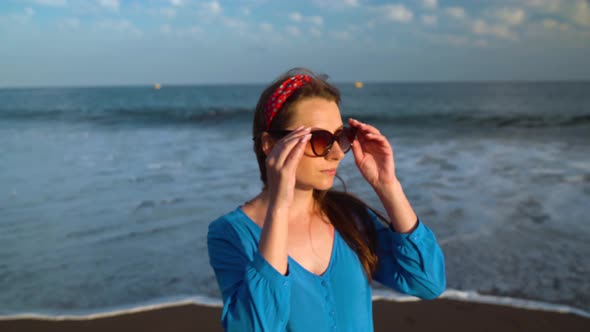 Portrait of a Woman in a Beautiful Blue Dress on a Black Volcanic Beach alt