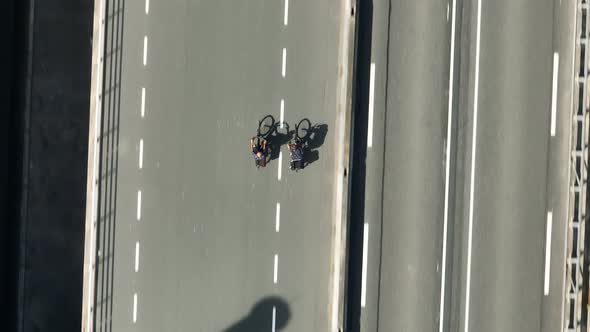 Two Cyclists Riding on a Road Bird's Eye View alt