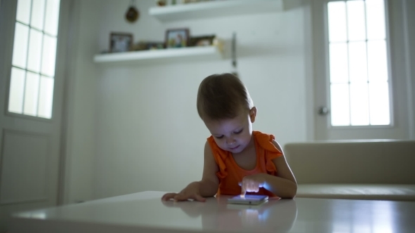 Young Child Plays On A Modern Smartphone In The Interior alt