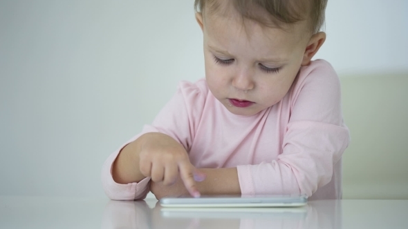 Young Child Plays On A Modern Smartphone In The Interior alt