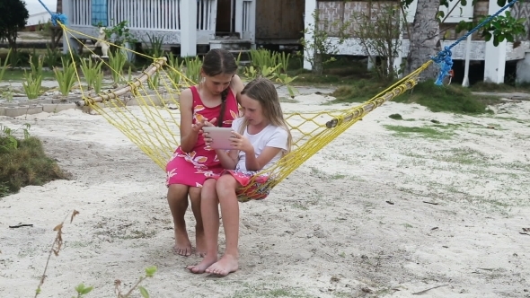 Girls In The Hammock With The Tablet On The Beach alt