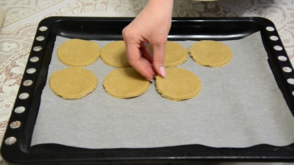 Woman Puts Raw Oatmeal Cookies on a Baking Sheet