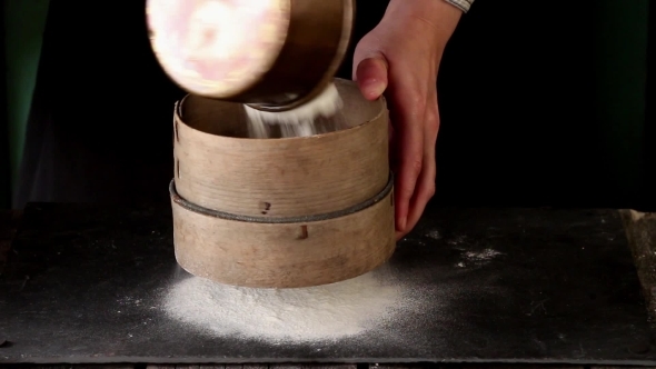 Female Hands Sifting Flour From Old Sieve On Black Kitchen Table
