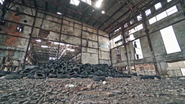 Big old empty factory with garbage and a pile of used rubber tyres inside. alt