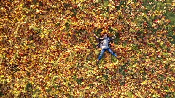 Aerial view A Cute Little Girl Lies in the Park on Yellow Fallen Leaves