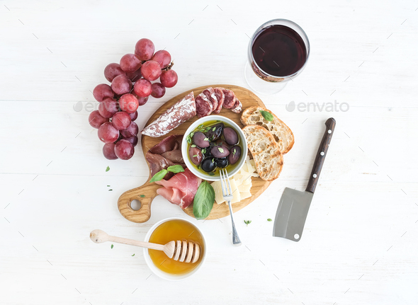 Wine appetizer set. Glass of red, grapes, parmesan cheese, meat variety, bread slices, pecan nuts