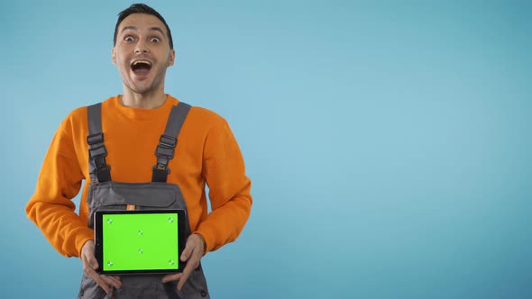 Excited, Happy, Extatic Young Man in Industrial Work Clothes Holding a Tablet and Checking the Green alt