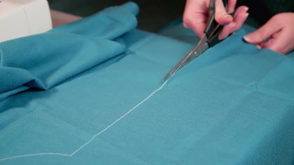 seamstress makes a pattern from fabric with scissors. Sewing clothes at home.