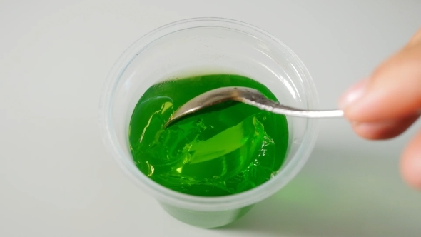 Lady's Hands Using Spoon To Scoop Green Jelly