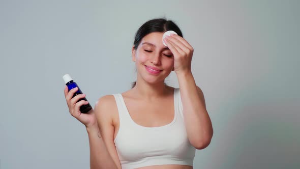 A Young Girl Applies Face Lotion to Her Face with a Sponge