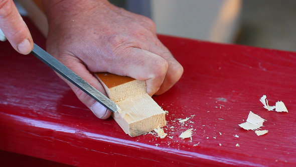 Carpenter Carving Piece Of Wood With Woodworking Tool