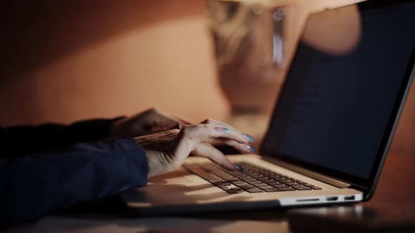 Female Hands Typing On a Laptop In The Evening