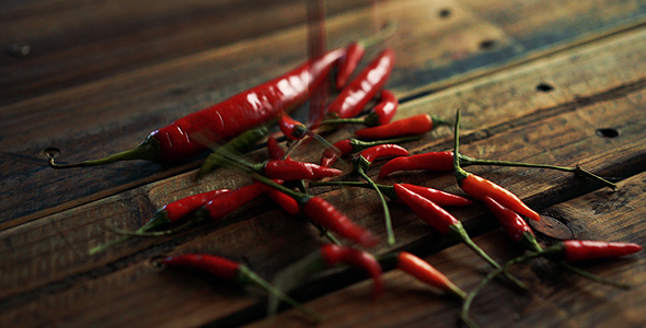 Red Cayenne And Birdseye Chilies Falling On Wooden Table